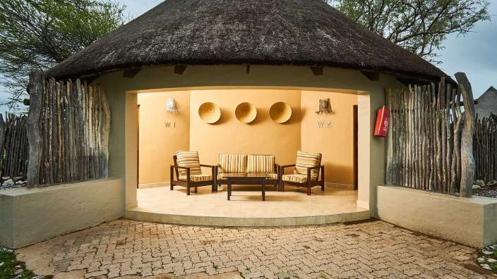 Ein Haus mit Strohdach und einem Couchtisch und Stühlen