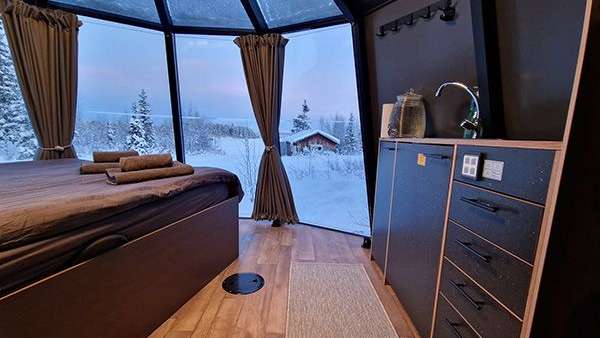 Ein Zimmer mit einem Bett und einem Fenster mit Blick auf den Schnee