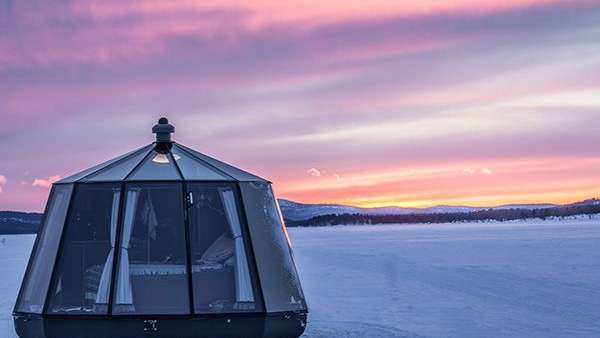 Ein Zelt steht inmitten eines schneebedeckten Feldes bei Sonnenuntergang