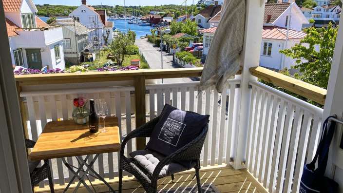 Ein Balkon mit einem Tisch und einem Stuhl und einer Flasche Wein