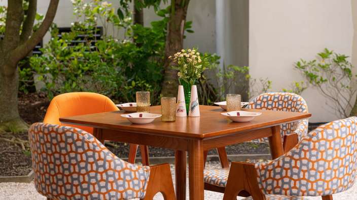 Ein Tisch mit vier Stühlen und einer Vase mit Blumen darauf