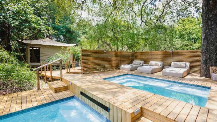 Ein Holzdeck mit einem Pool und Liegestühlen darauf