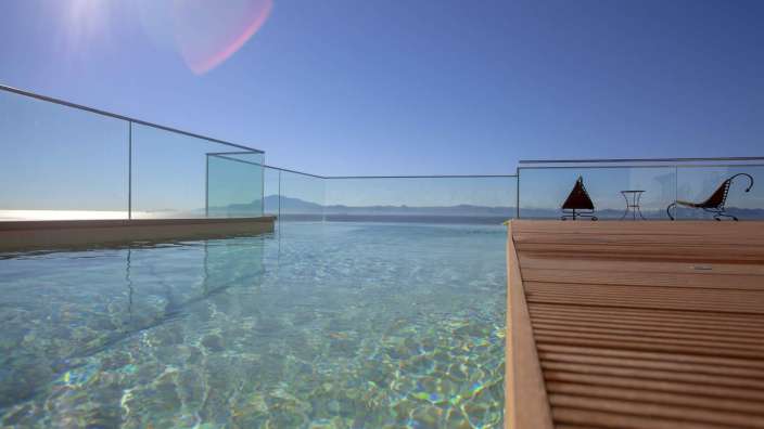 Ein schwimmbad mit einem glasgeländer und einem holzdeck