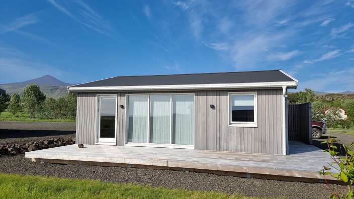 Ein kleines Haus mit einem roten Auto davor