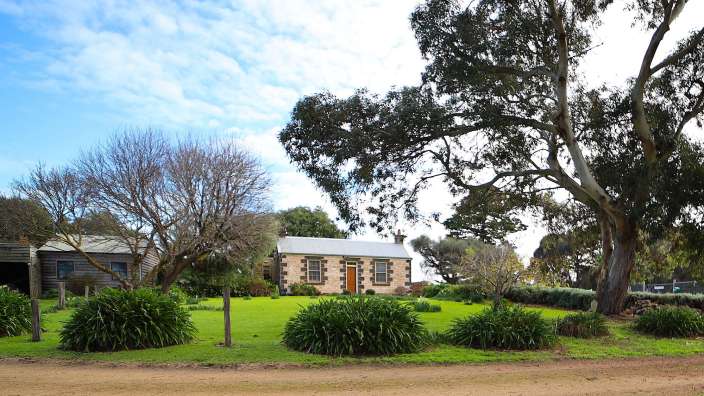 Ein kleines Steinhaus mit einer orangefarbenen Tür