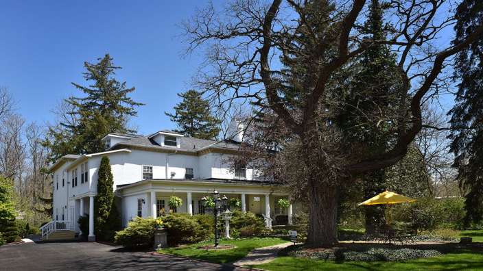 Ein großes weißes Haus mit einer großen Veranda und einem gelben Sonnenschirm
