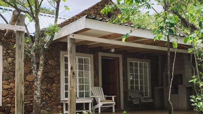 Ein Steinhaus mit einer Veranda und zwei Stühlen darauf