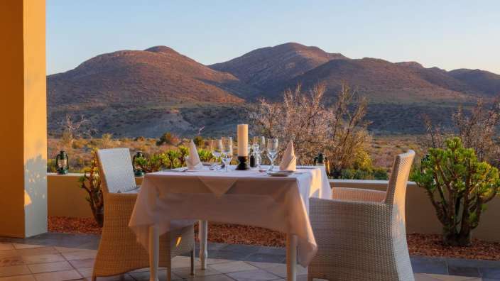 Ein Tisch und Stühle auf einer Terrasse mit Blick auf die Berge