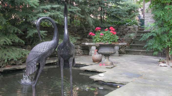 Eine Statue eines Krans steht neben einem Teich