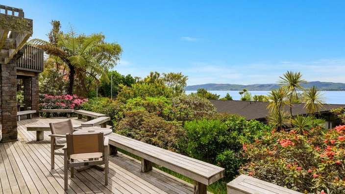 Ein Holzdeck mit Stühlen und einem Tisch mit Blick auf einen See