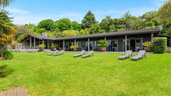 Eine Reihe von Liegestühlen steht auf einem grünen Rasen vor einem großen Haus