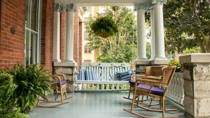 Eine Veranda mit einer Schaukel und zwei Schaukelstühlen