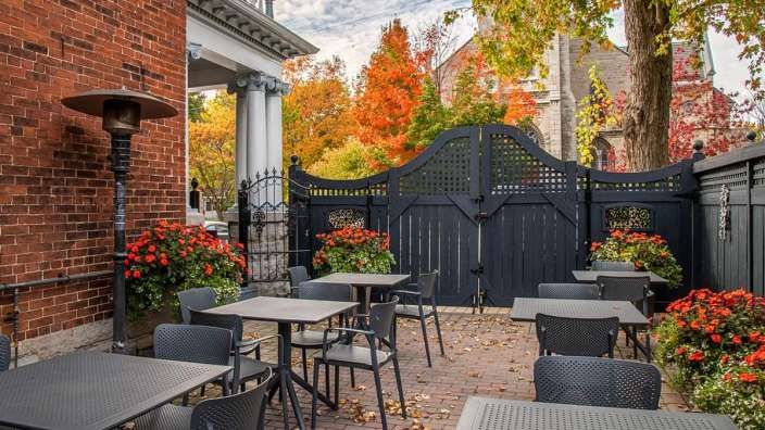 Eine Terrasse mit Tischen und Stühlen vor einem Backsteingebäude