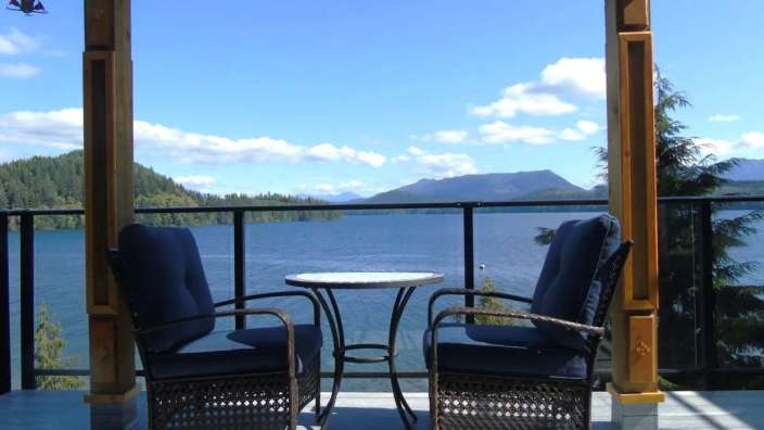 Zwei Stühle und ein Tisch auf einem Deck mit Blick auf einen See