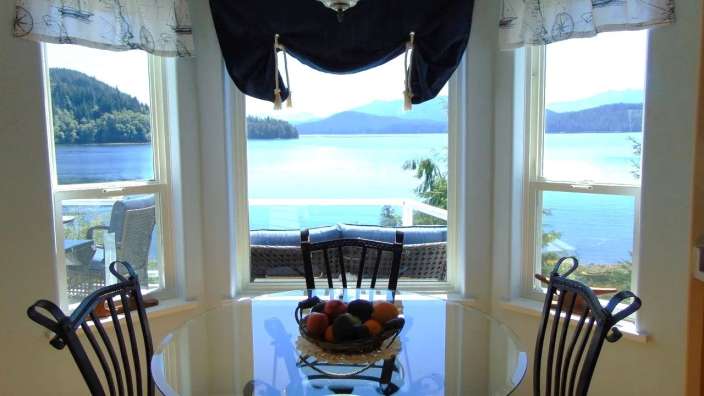 Ein Esszimmer mit einem Tisch und Stühlen mit Blick auf einen See