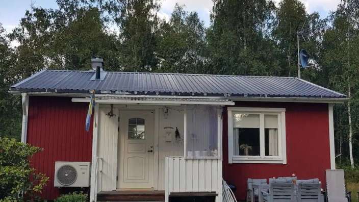Ein rotes Haus mit einer weißen Tür und einem schwarzen Dach