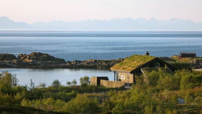 Ein Haus mit einem grünen Dach steht in der Nähe des Ozeans