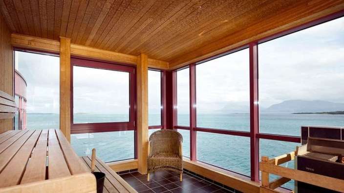 Eine Sauna mit vielen Fenstern mit Blick auf das Meer