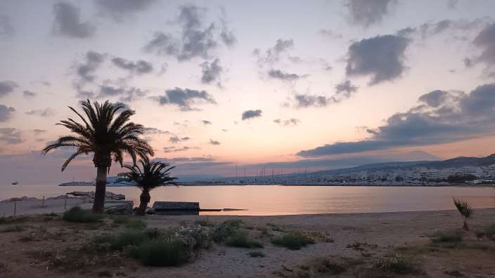 Ein Strand mit Palmen und einem Sonnenuntergang im Hintergrund
