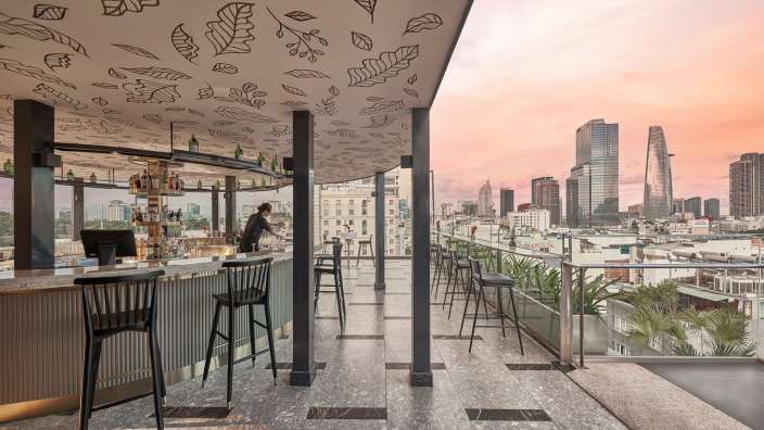 Ein Mann steht an einer Bar mit Blättern an der Decke