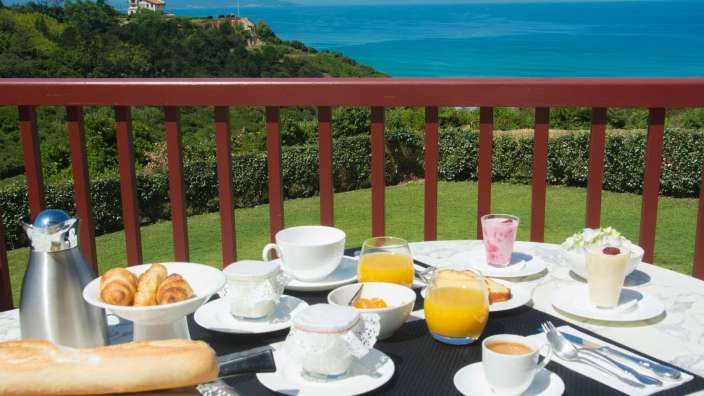 Ein Tisch mit Essen und Getränken auf einem Balkon mit Blick auf den Ozean