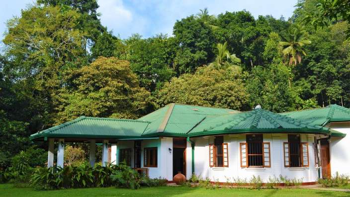 Ein weißes Haus mit einem grünen Dach und vielen Fenstern