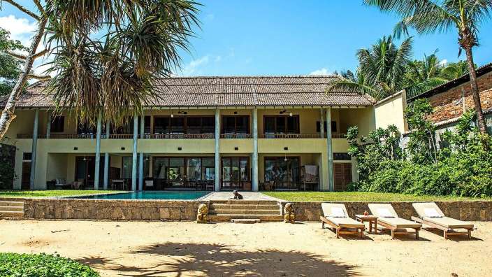 Ein großes Haus mit einem Pool und Liegestühlen im Vordergrund