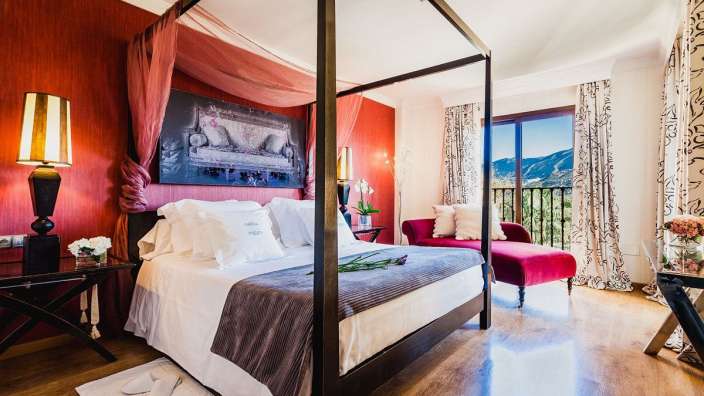 Ein Schlafzimmer mit einem Himmelbett und einem roten Stuhl