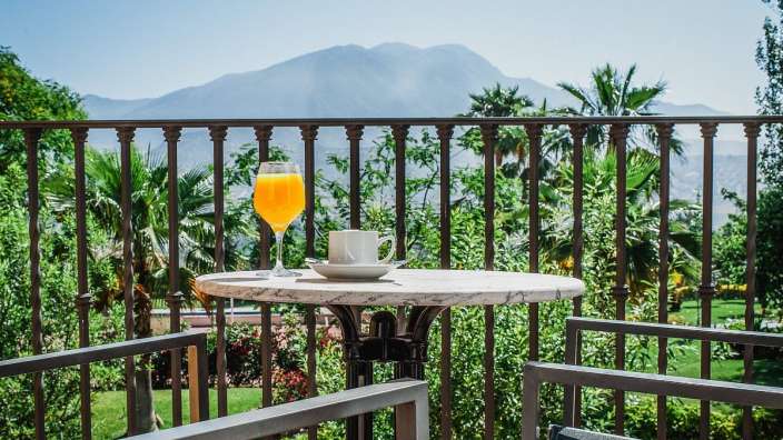 Ein Tisch mit einer Tasse Kaffee und einem Glas Orangensaft auf einem Balkon