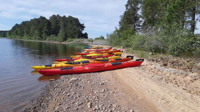 Eine Reihe roter und gelber Kajaks am Ufer eines Sees