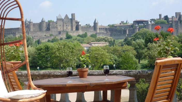 Ein Tisch mit zwei Gläsern Wein auf einem Balkon mit einem Schloss im Hintergrund