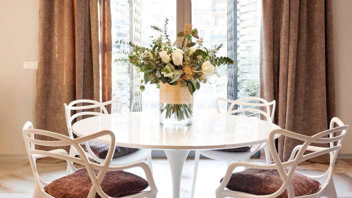 Ein weißer Tisch mit vier weißen Stühlen und einer Vase mit Blumen darauf