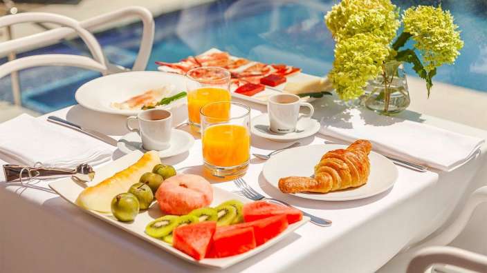Auf einem weißen tisch steht ein teller mit früchten und einem croissant