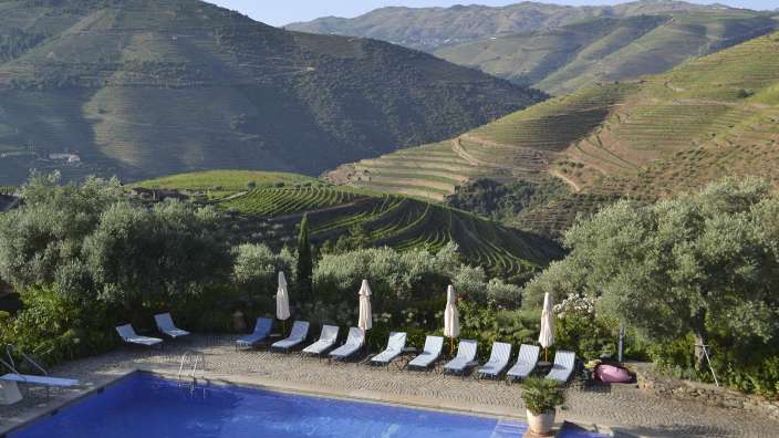 Ein Pool mit Stühlen und Sonnenschirmen umgeben von Bergen