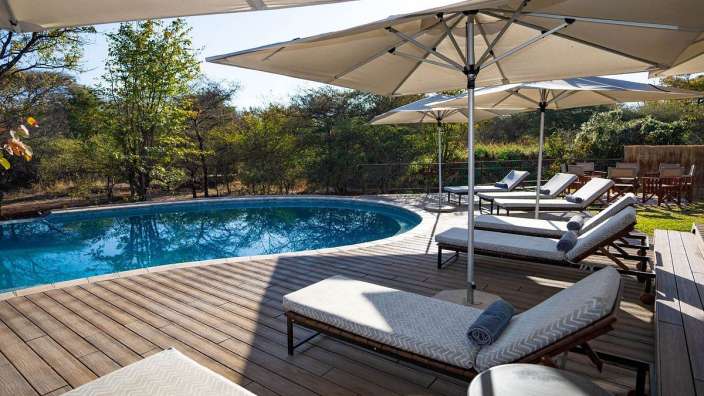 Liegestühle und Sonnenschirme umgeben einen großen Swimmingpool