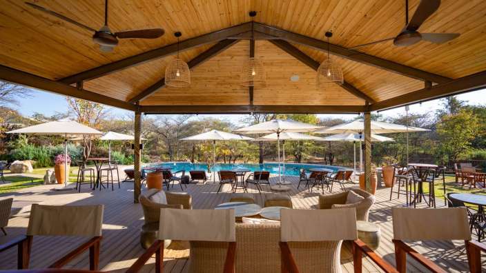 Ein Wohnzimmer mit Blick auf einen Pool und Tische und Stühle