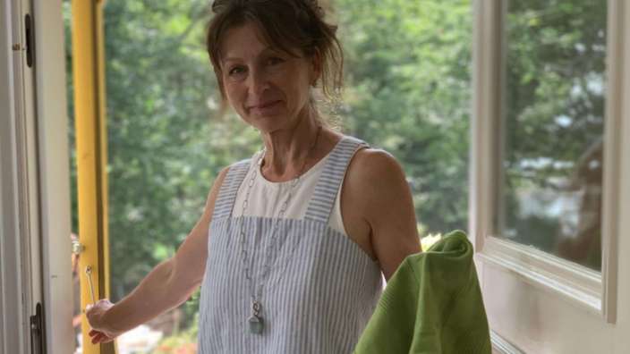 Eine frau in einem gestreiften kleid steht auf einer veranda