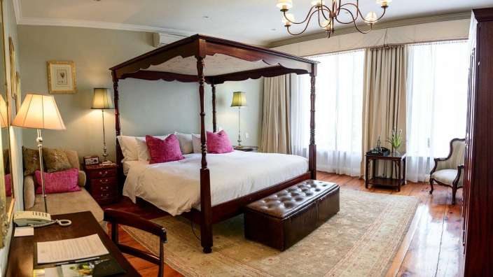 Ein Schlafzimmer mit einem Himmelbett und einem Stuhl