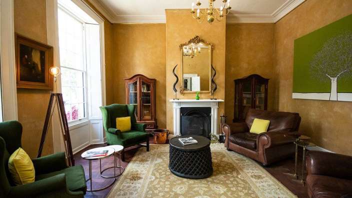 Ein Wohnzimmer mit grünen Stühlen und einem Kamin