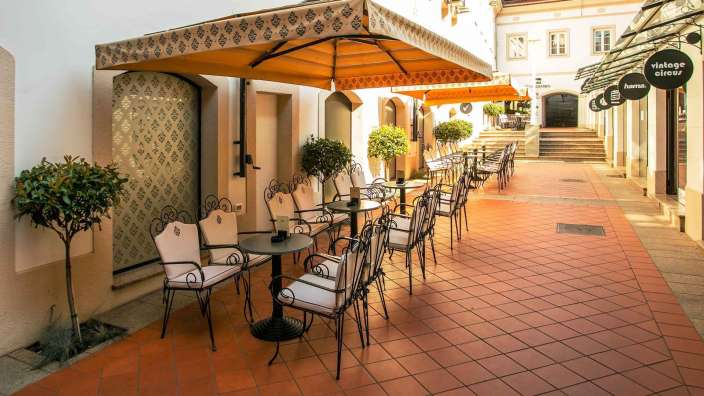 Eine Reihe von Tischen und Stühlen vor einem Gebäude mit einem Schild, das sagt ' bistro '