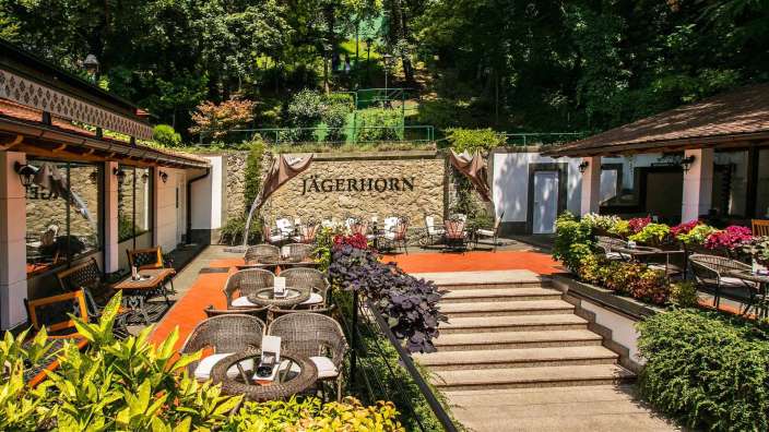 Eine Terrasse mit Tischen und Stühlen vor einem Gebäude mit der Aufschrift jagerhorn
