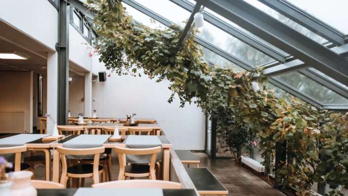 Tische und Stühle in einem Restaurant mit Blättern an der Decke