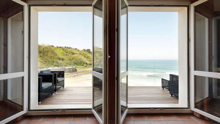 Ein Wohnzimmer mit offenen Fenstern mit Blick auf den Ozean