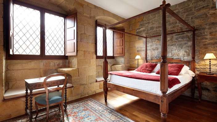 Ein Schlafzimmer mit einem Himmelbett und einem Schreibtisch