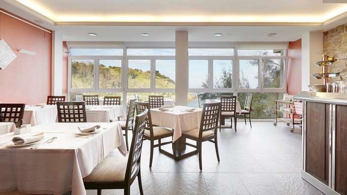 Tische und Stühle in einem Restaurant mit vielen Fenstern