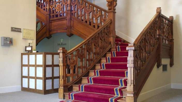 Eine hölzerne Treppe mit einem roten Teppich in einem Gebäude