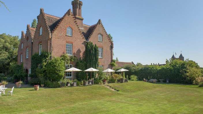 Ein großes Backsteingebäude mit vielen Sonnenschirmen und Stühlen