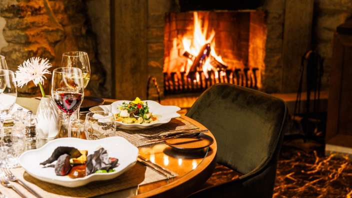 Ein Tisch mit Essen und Gläsern vor einem Kamin