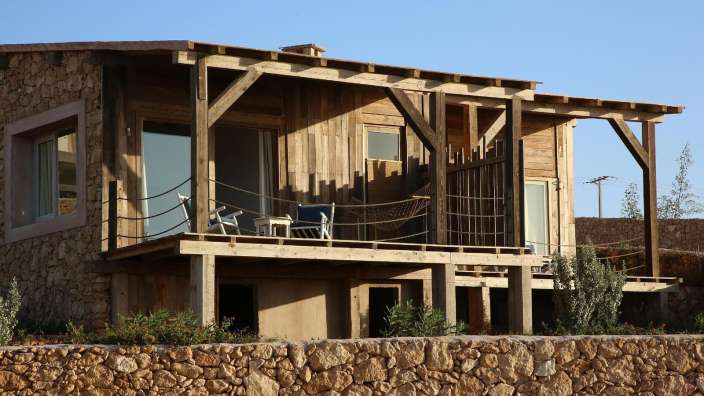 Ein kleines Holzhaus mit einer Steinmauer dahinter