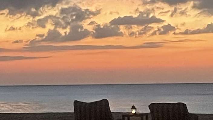 Sonnenuntergang am Strand mit zwei Stühlen und einem Tisch